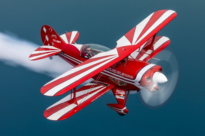 Red and white Pitts S-2B biplane performing aerobatics