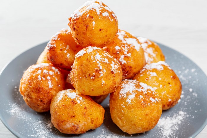 Fried pastry balls with powdered sugar on a plate