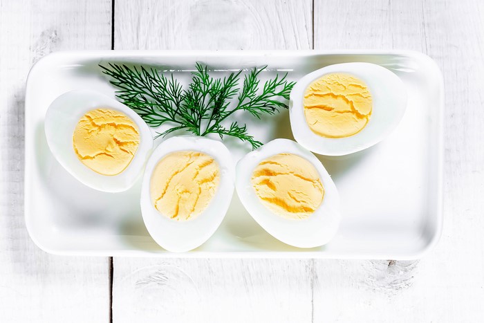 Hard-boiled eggs with dill on white wooden planks