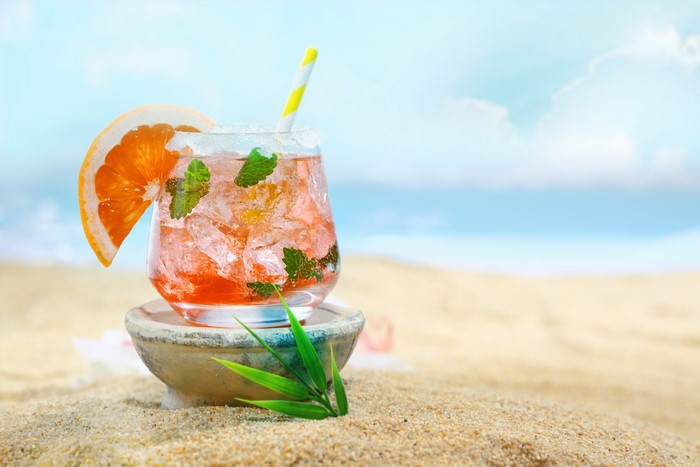 Cocktail with orange slice and mint on beach