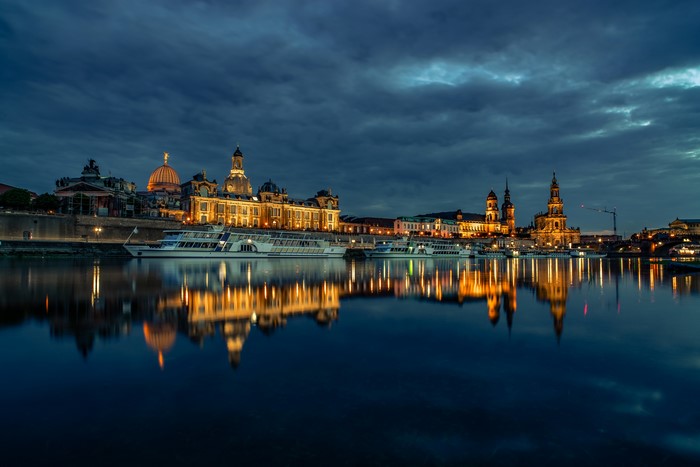 Dresden skyline with illuminated buildings and riverboats at dusk