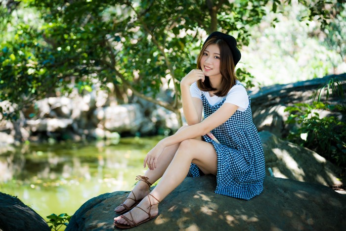 Smiling Woman Sitting on Rock Outdoors