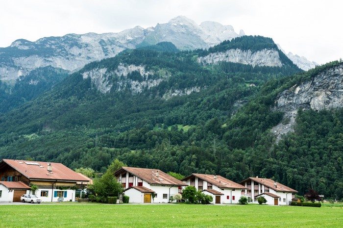 Houses in Meiringen valley, Switzerland with mountains and forests