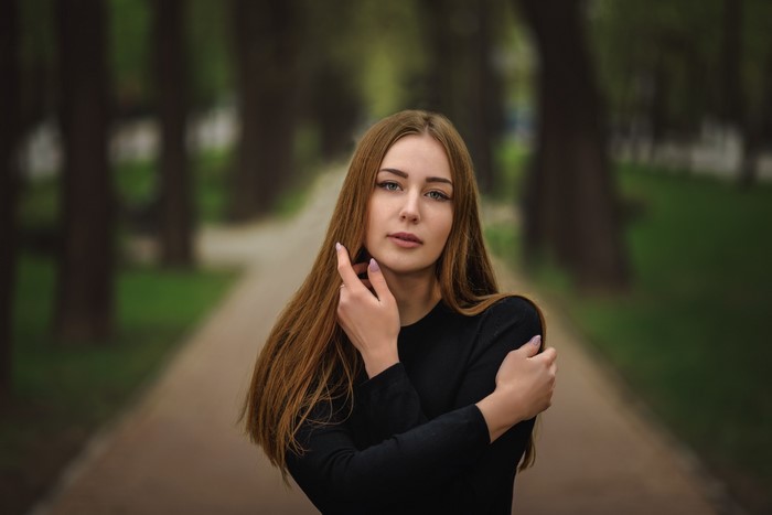 Brown-haired woman with hands near face in park