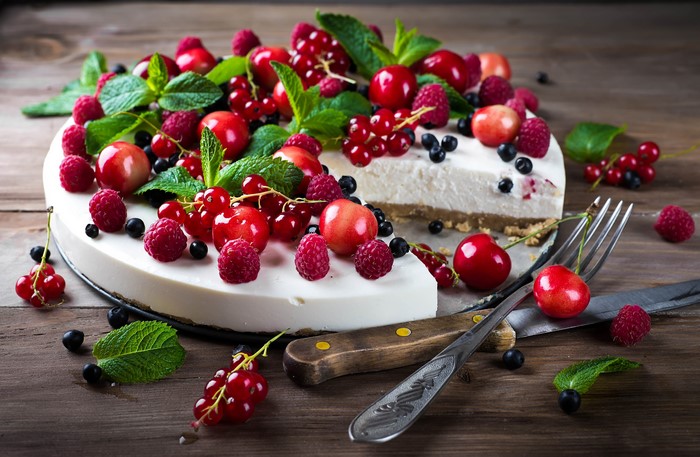 Cheesecake with berries and mint on wooden planks