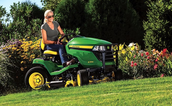 Woman on John Deere X394 lawn tractor mowing grass