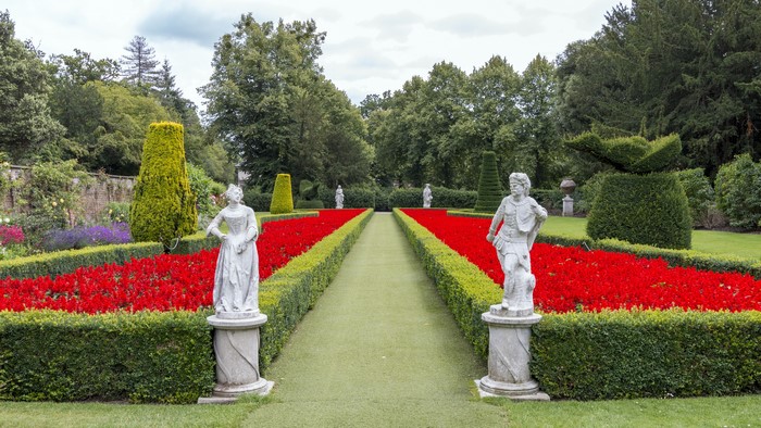 Formal garden with statues and red flowers