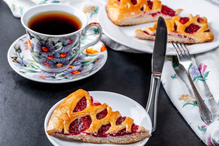 Tea cup and saucer with raspberry pie slices and cutlery