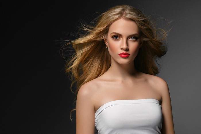 Blonde woman with red lipstick on gray background