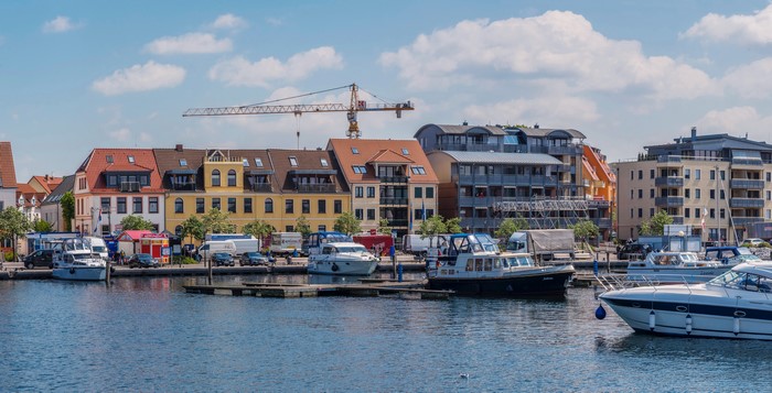 Boats docked in a marina with buildings and a crane in Waren, Germany
