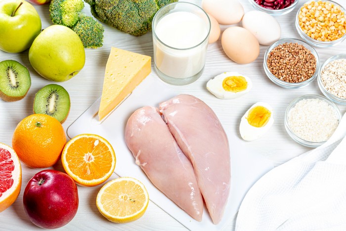 Still-life of food: chicken, eggs, cheese, fruits, and grains