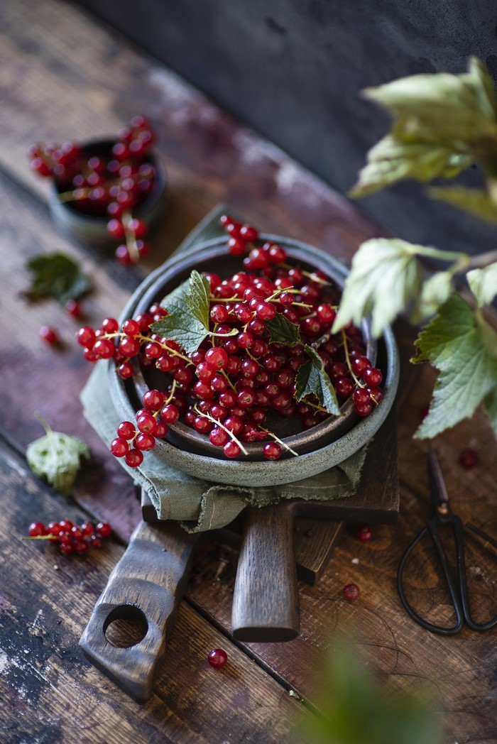 Red currants in a bowl on wooden planks