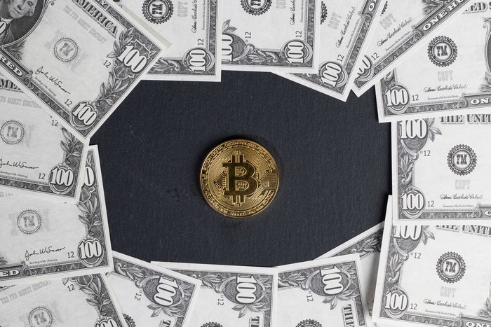 Bitcoin coin surrounded by US dollar banknotes