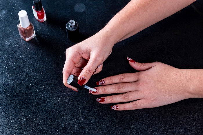 Woman applying wine-colored nail polish