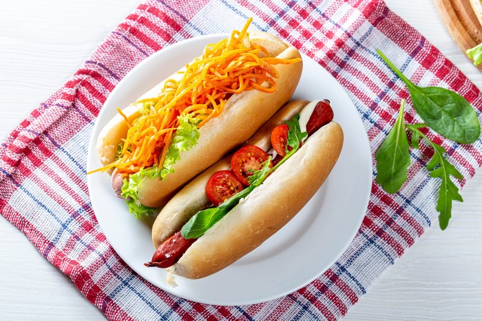 Two hot dogs with toppings on a plate