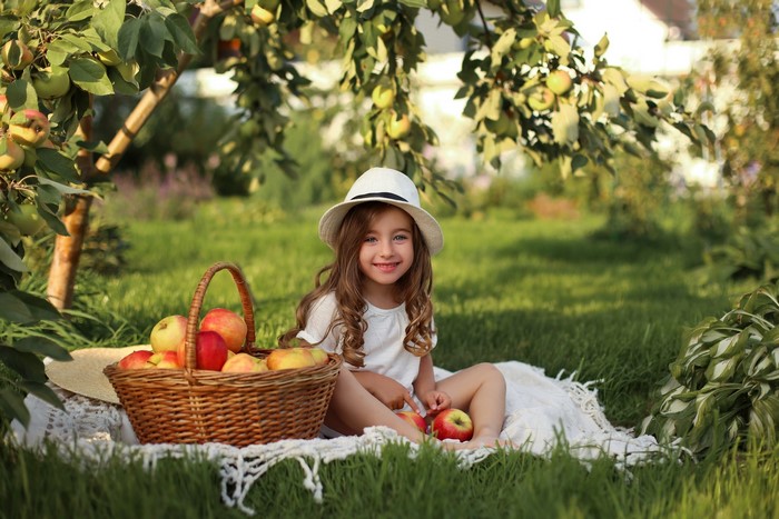Girl in a hat with a basket of apples