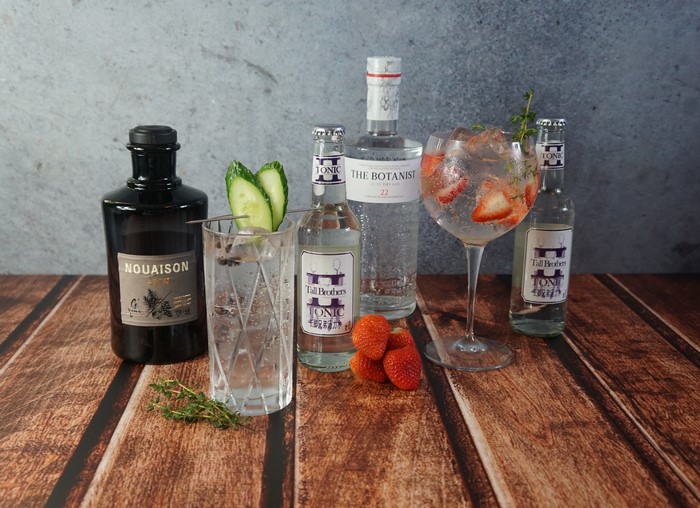 Gin bottles, tonic, cocktail, strawberries, and cucumber