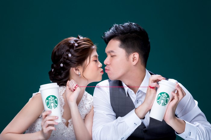 Couple kissing holding Starbucks cups