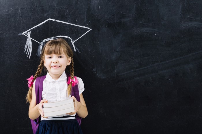 Girl with graduation cap drawing and books