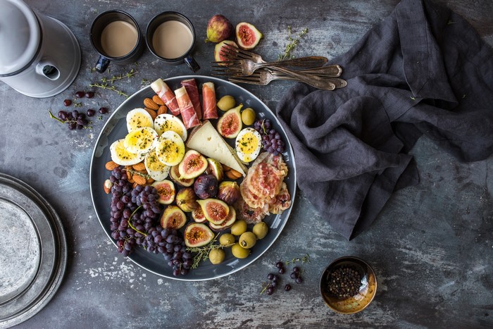 Charcuterie board with figs, eggs, cheese, and grapes