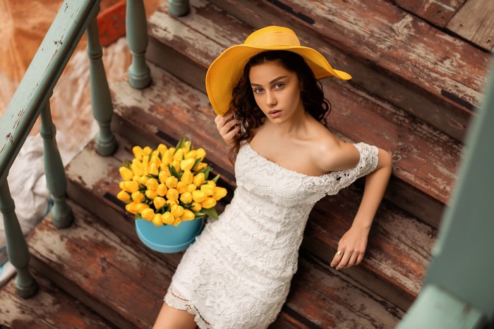 Natia Gachava in a white dress and yellow hat on stairs