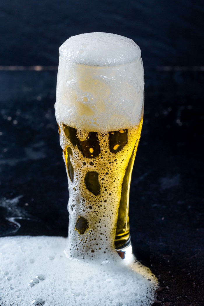 Beer overflowing from a highball glass