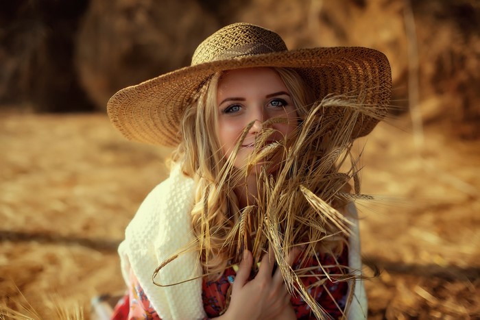Woman in straw hat with wheat in a field