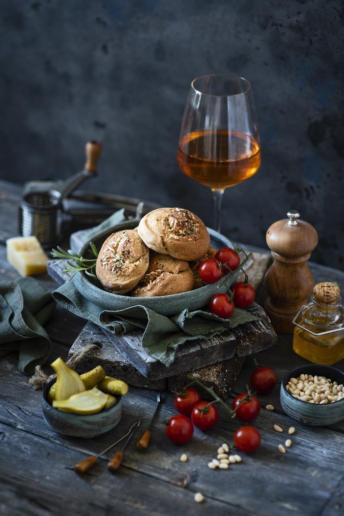 Still life with wine, bread rolls, tomatoes, and pickles
