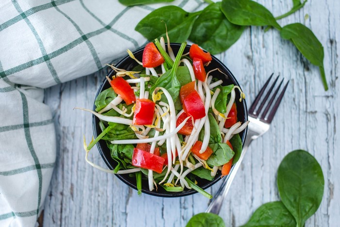 Spinach salad with bean sprouts and red bell pepper in a bowl