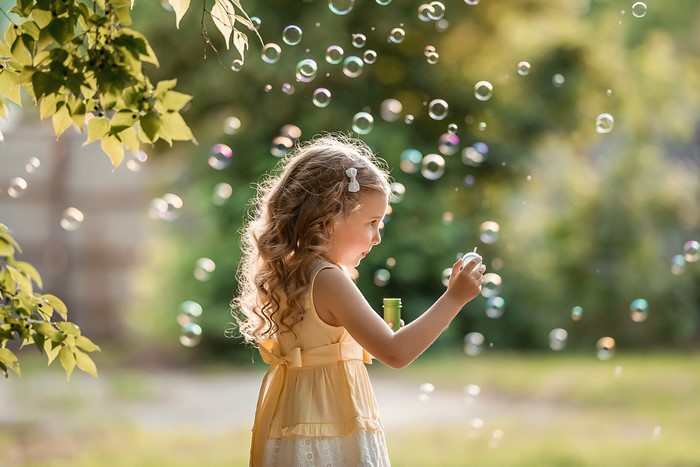 Little girl blowing soap bubbles in a park