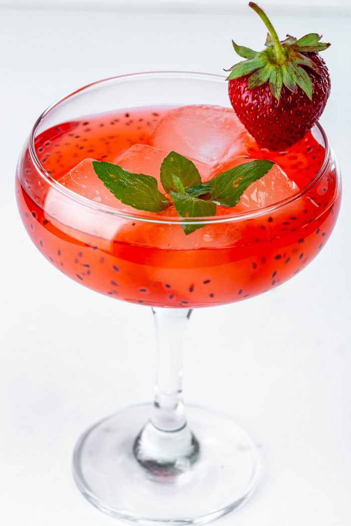 Strawberry cocktail with ice and mint in a coupe glass