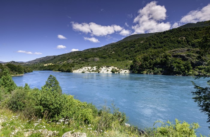 Blue river flowing through a green mountainous landscape in Patagonia, Chile
