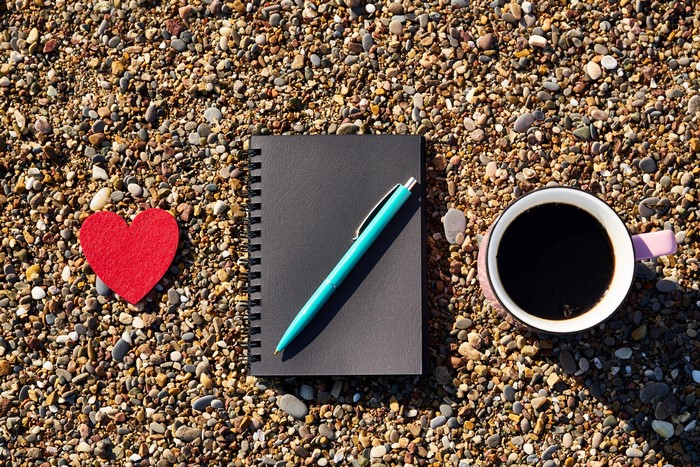 Heart, Notepad, Pen, and Coffee on Pebbles