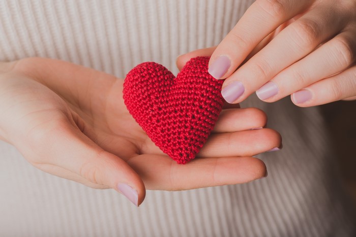 Hands holding a red knitted heart