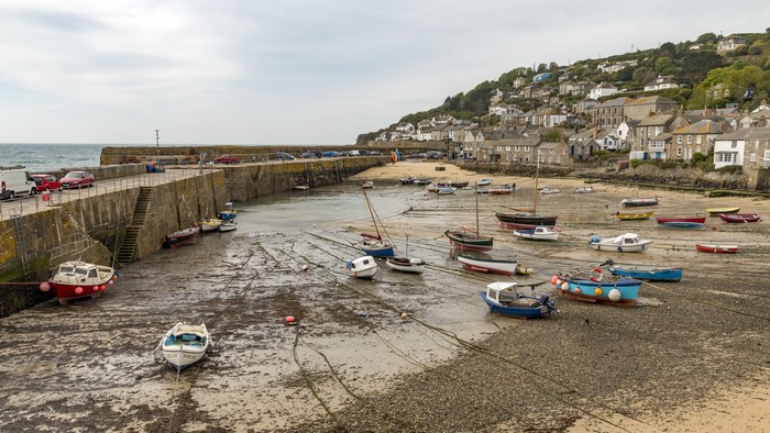 Mousehole Harbour with boats and houses on a hill