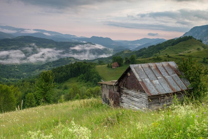 Rustic cabin in Romanian mountains with misty valleys