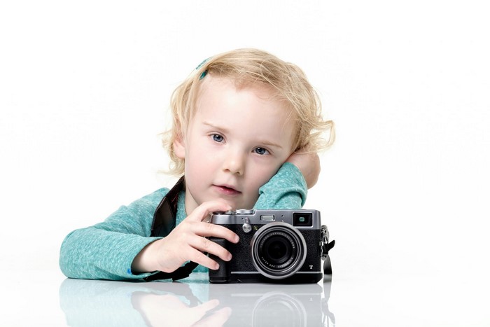 Young girl with a camera on a white background