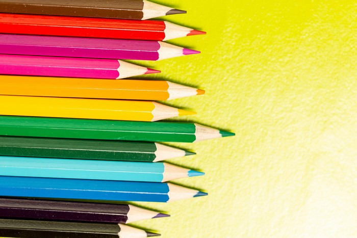 A row of colored pencils on a yellow background