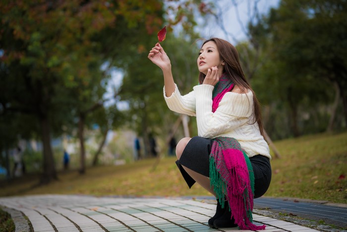 Asian woman in white sweater holding a leaf
