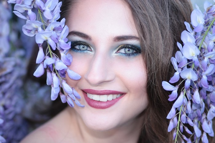 Woman with blue eye makeup and purple flowers