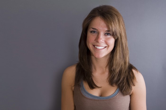 Smiling Woman with Brown Hair and Gray Background
