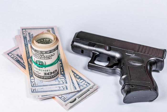 Black pistol and US dollar bills on a white background