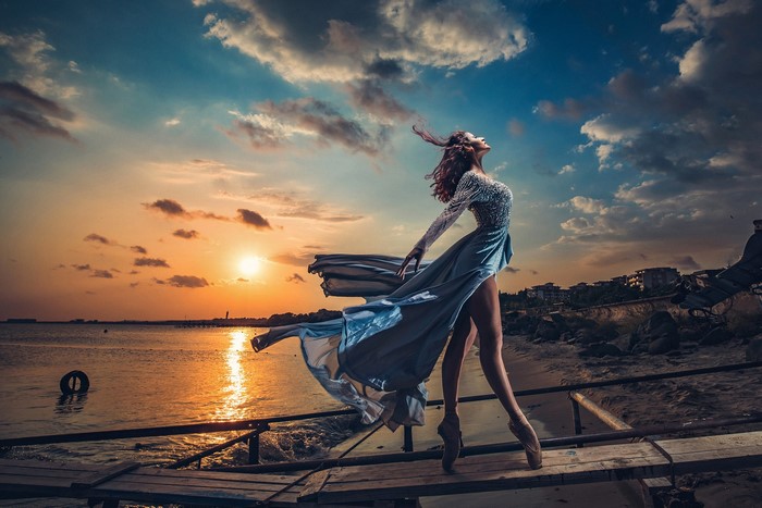 Ballerina posing by the sea at sunset