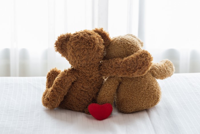 Two teddy bears hugging with a red heart