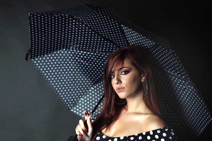 Woman with polka dot umbrella and dramatic makeup
