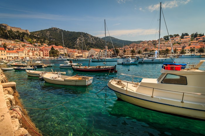 Boats in a harbor with Hvar town and hills in the background
