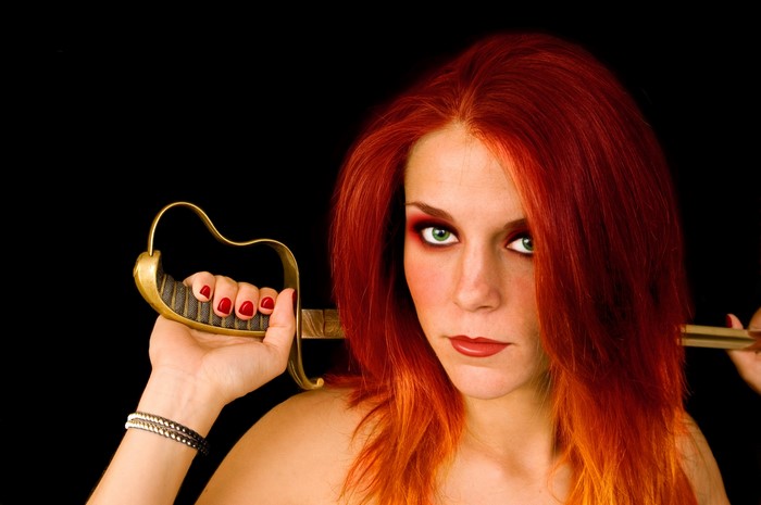 Redhead woman with sabre on black background