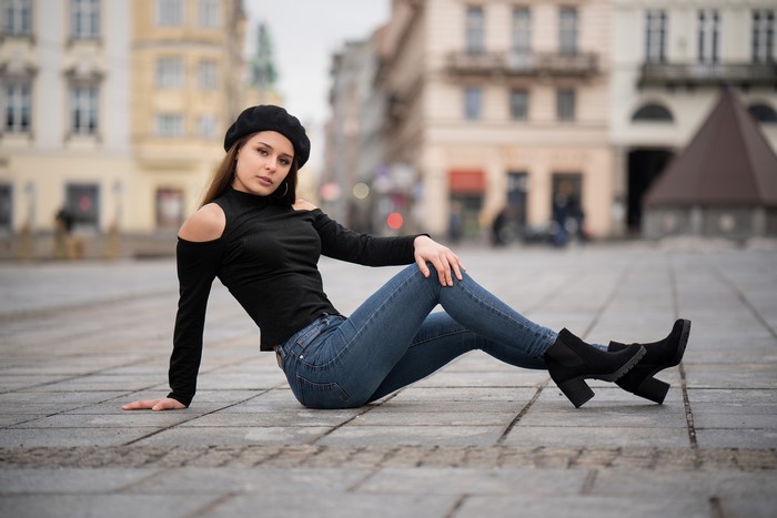 Woman in black beret and jeans posing outdoors