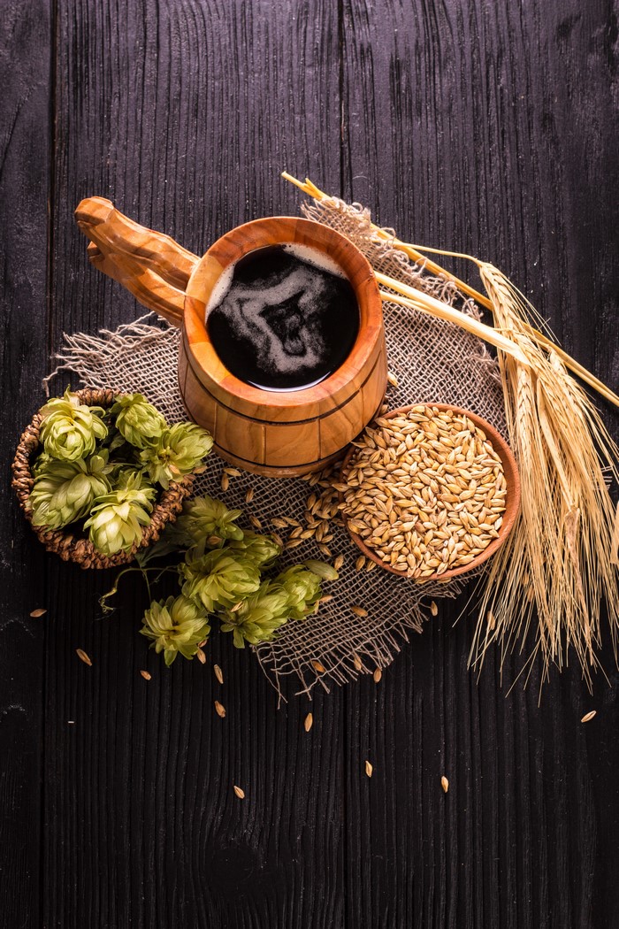 Beer mug with hops and barley on wood