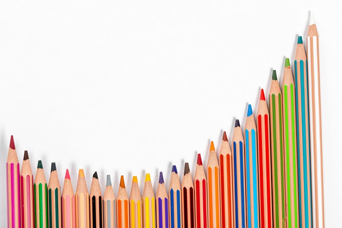 Colored pencils arranged in a rising graph pattern on a white background